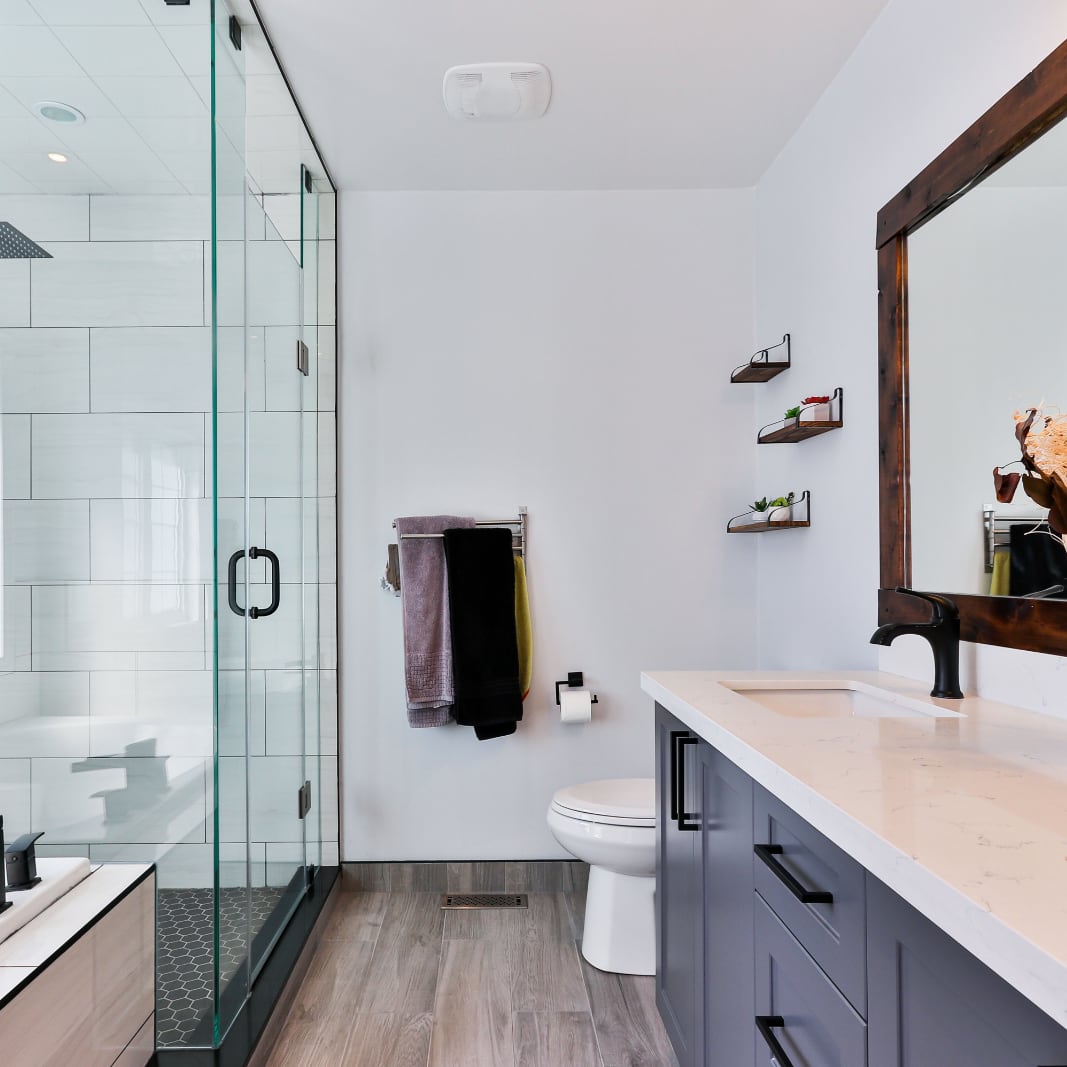 Modern bathroom with glass shower, white counter, and gray vanity